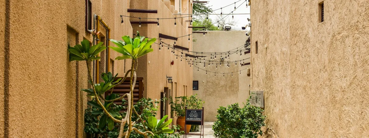 A narrow lane in the Al Fahidi Historical Neighbourhood, lined with traditional coral-and-gypsum buildings and wind towers