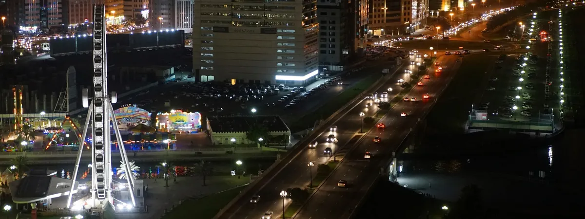The Eye of the Emirates Ferris wheel lit up at night beside the Al Qasba canal in Sharjah