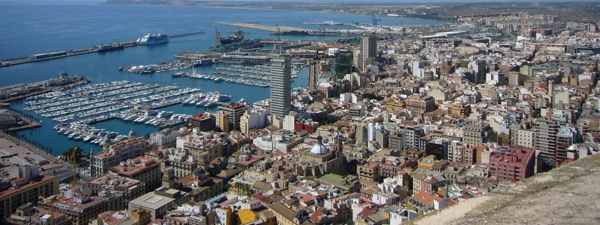 The port and old town of Alicante seen from Santa Bárbara Castle, with the marina, Explanada, and Mediterranean coastline beyond