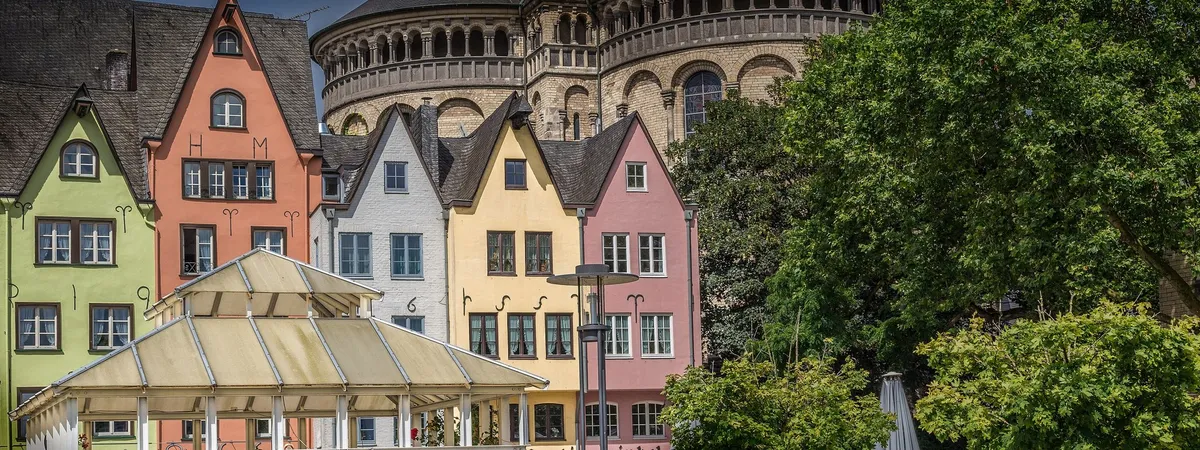 Row of colorful gabled houses at the Fischmarkt in Cologne's old town, with the round Romanesque tower of Groß St. Martin rising behind them
