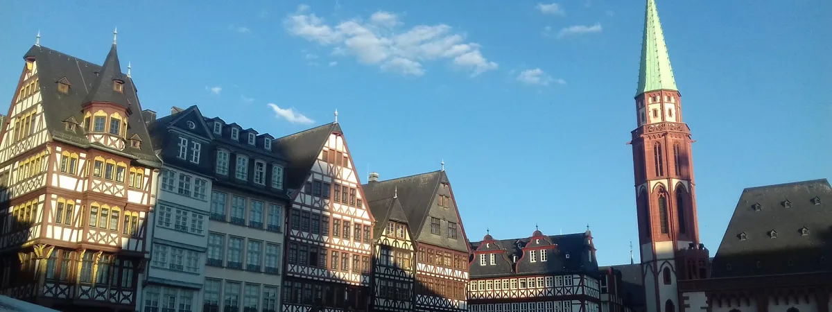 Half-timbered houses on the Römerberg square in Frankfurt's old town, with the Alte Nikolaikirche's tower rising behind them