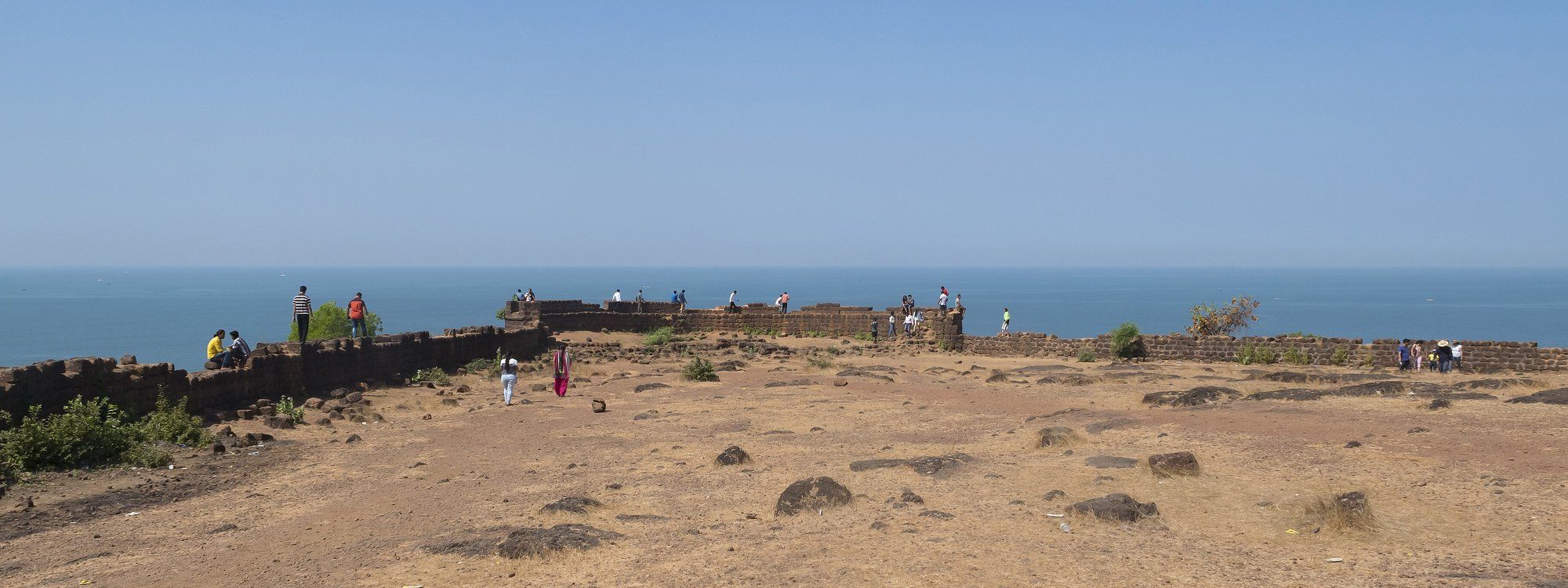 Visitantes caminando por las murallas frente al mar del Fuerte Chapora, cerca de la playa de Vagator