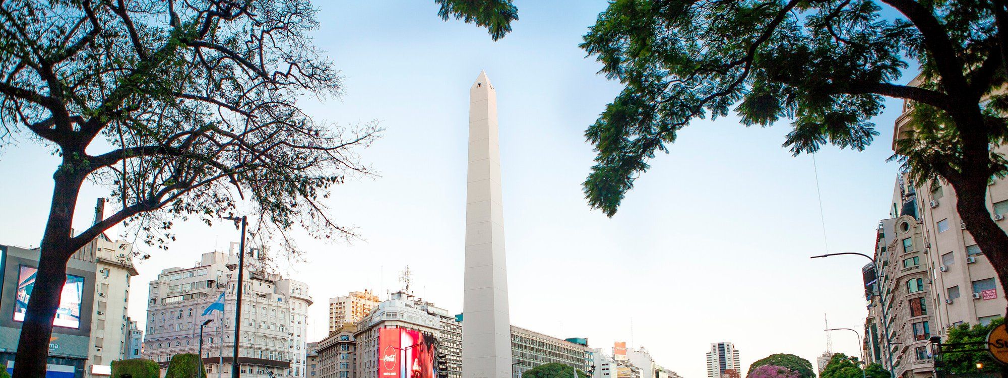 El Obelisco de Buenos Aires elevándose sobre la Avenida 9 de Julio, enmarcado por árboles a ambos lados