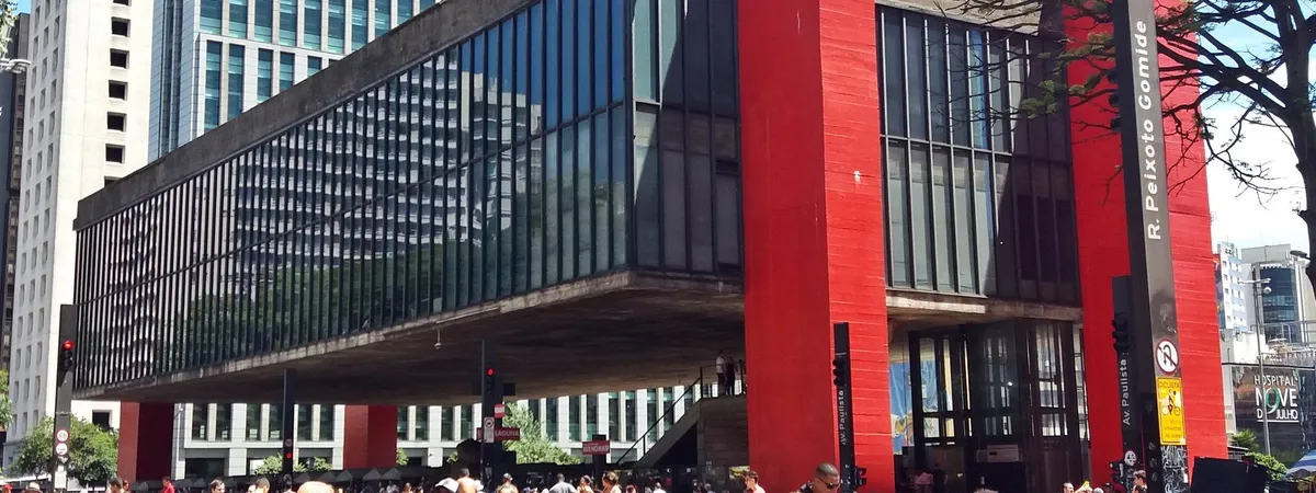 El edificio rojo y de vidrio del MASP, suspendido sobre su plaza en la Avenida Paulista y rodeado de peatones