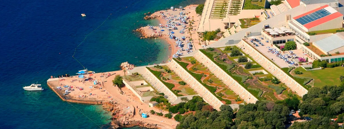 Aerial view of a large resort hotel complex with terraced gardens and a pebble beach on the Babin Kuk peninsula