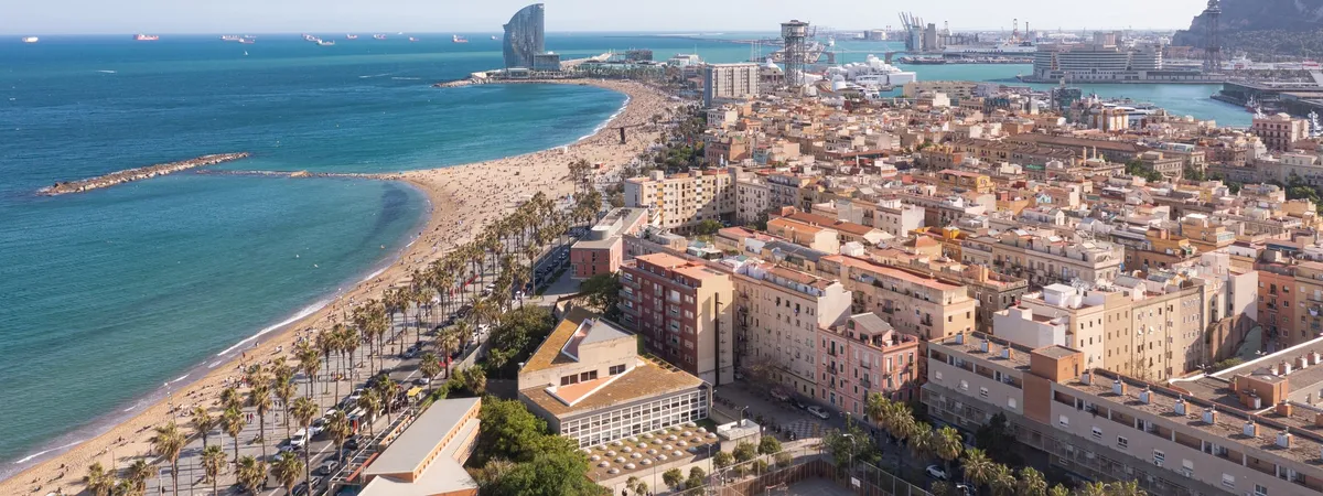 Aerial view of Barceloneta beach curving along the Mediterranean, with the W Hotel and Port Vell in the background