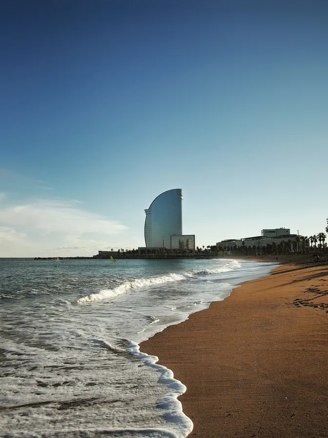 La playa de Barceloneta al atardecer, con el hotel W Barcelona en forma de vela en el paseo marítimo