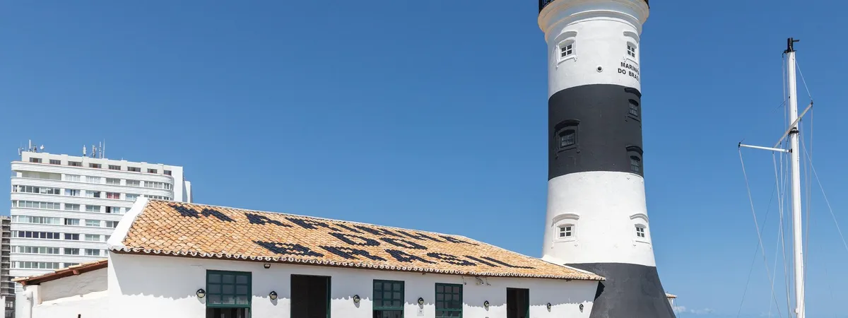 El faro de Farol da Barra, a rayas blancas y negras, elevándose sobre su fuerte encalado en la costa de Salvador