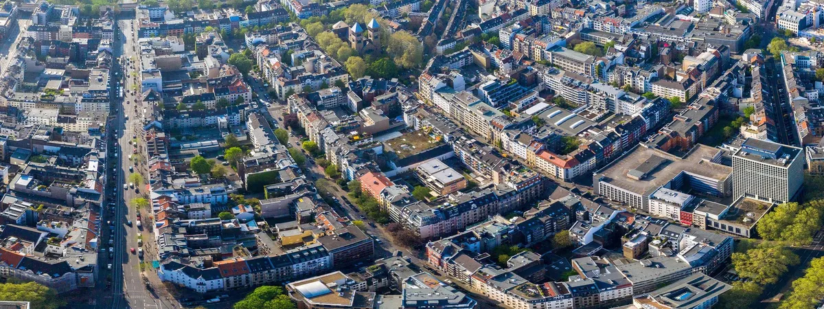 Aerial view over the Belgian Quarter's dense grid of tree-lined streets and rooftops, with the twin spires of St. Michael's Church rising above the neighborhood