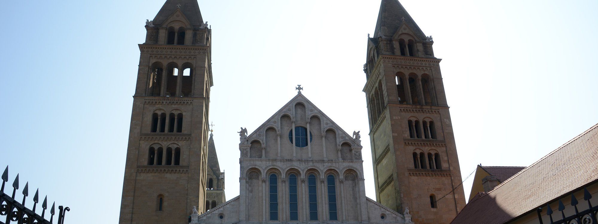 The twin Romanesque bell towers and gabled facade of Pécs Cathedral rising above the historic center