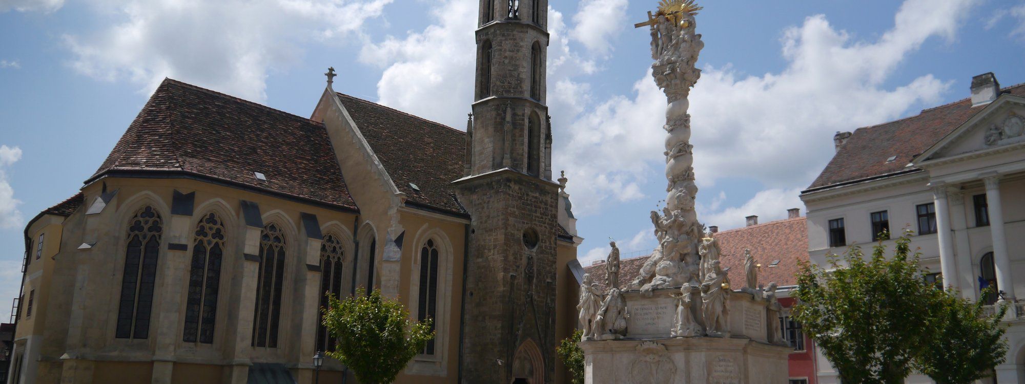 La torre gótica de la Iglesia de la Cabra y la Columna de la Santísima Trinidad se alzan sobre Fő tér, en el casco antiguo de Sopron