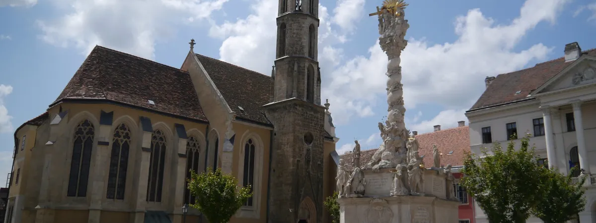 The Gothic tower of the Goat Church and the Holy Trinity Column rising above Fő tér in Sopron's old town