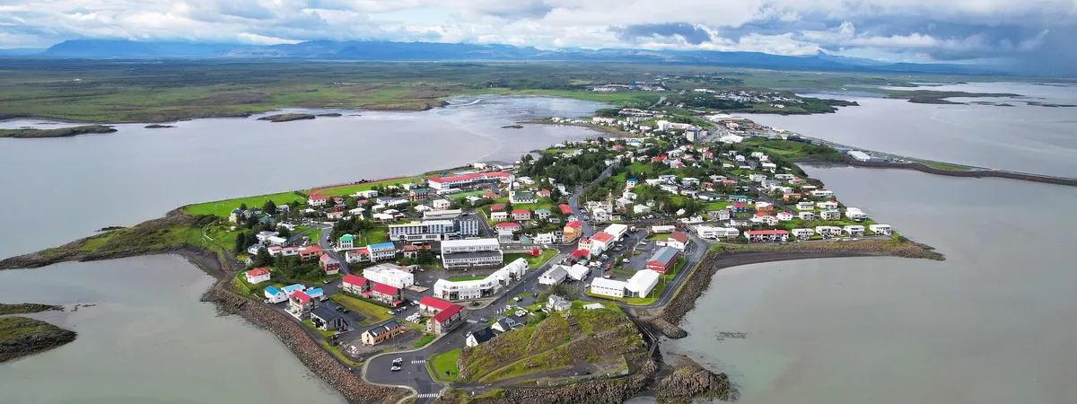 Aerial view of Borgarnes on its narrow peninsula in Borgarfjörður, with the old town clustered at the tip and mountains behind