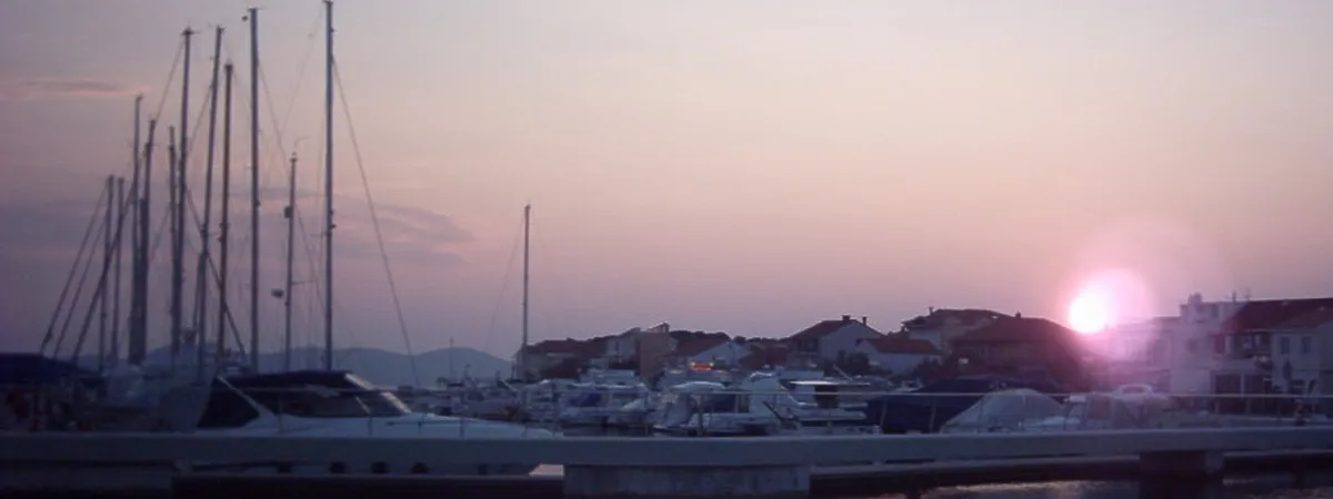 Sailboats and motor yachts moored at Marina Borik at dusk, with Zadar's coastline in the background