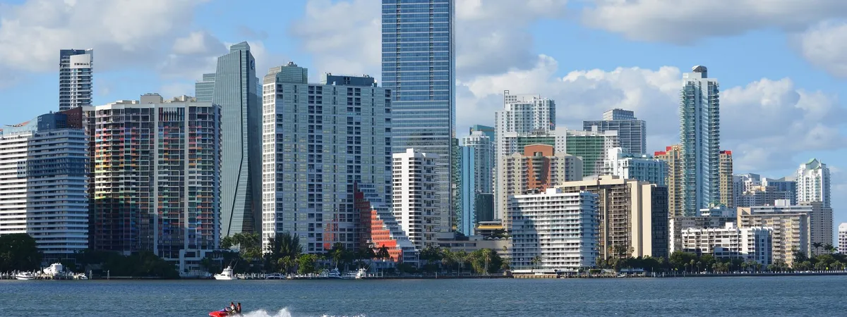 Brickell's skyline of high-rises seen across the water from the Rickenbacker Causeway, with a boat passing in the foreground