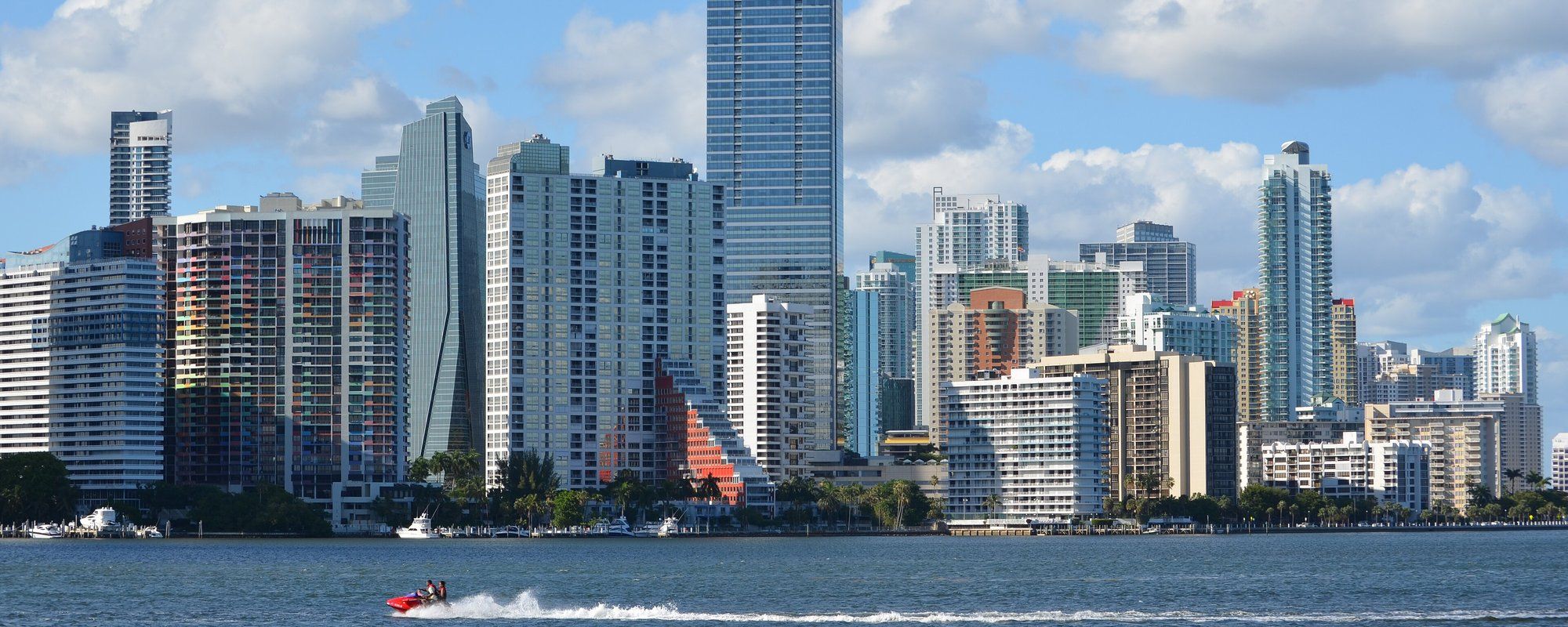Brickell's skyline of high-rises seen across the water from the Rickenbacker Causeway, with a boat passing in the foreground