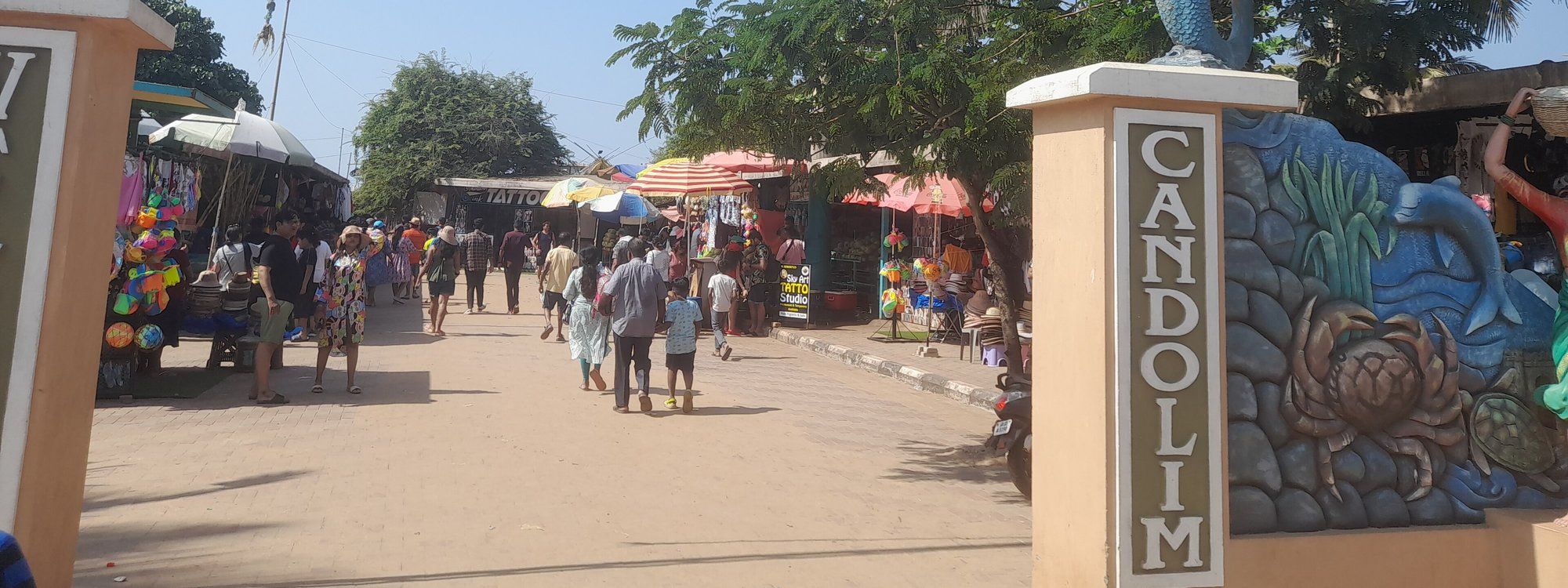 A carved stone gateway marking the entrance to Candolim Beach's market lane