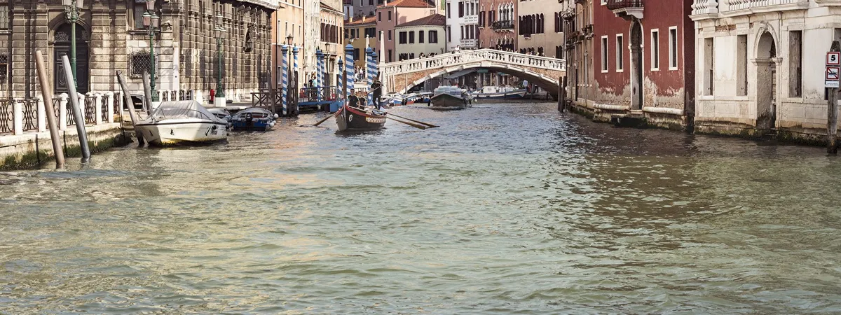 The Cannaregio Canal in Venice, lined with pastel-colored buildings and crossed by the white stone Ponte delle Guglie bridge