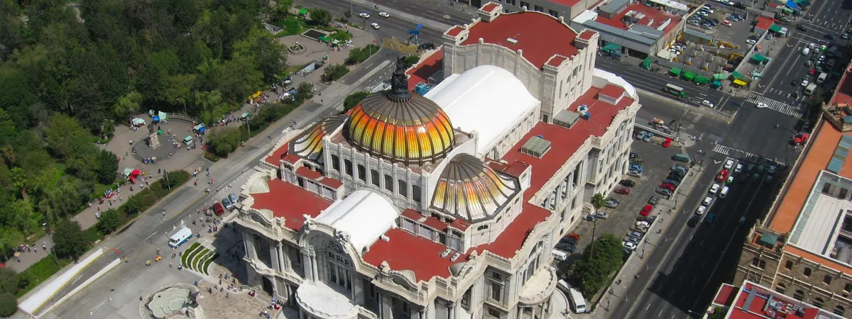 Aerial view of the Palacio de Bellas Artes in Mexico City's Centro Histórico, showing its tiled domes and the surrounding Alameda Central