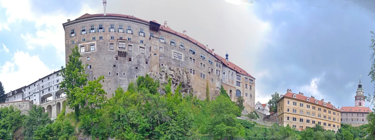 Elevated view of Český Krumlov Castle rising over the Vltava river, with the castle's colorful tower visible on the far side