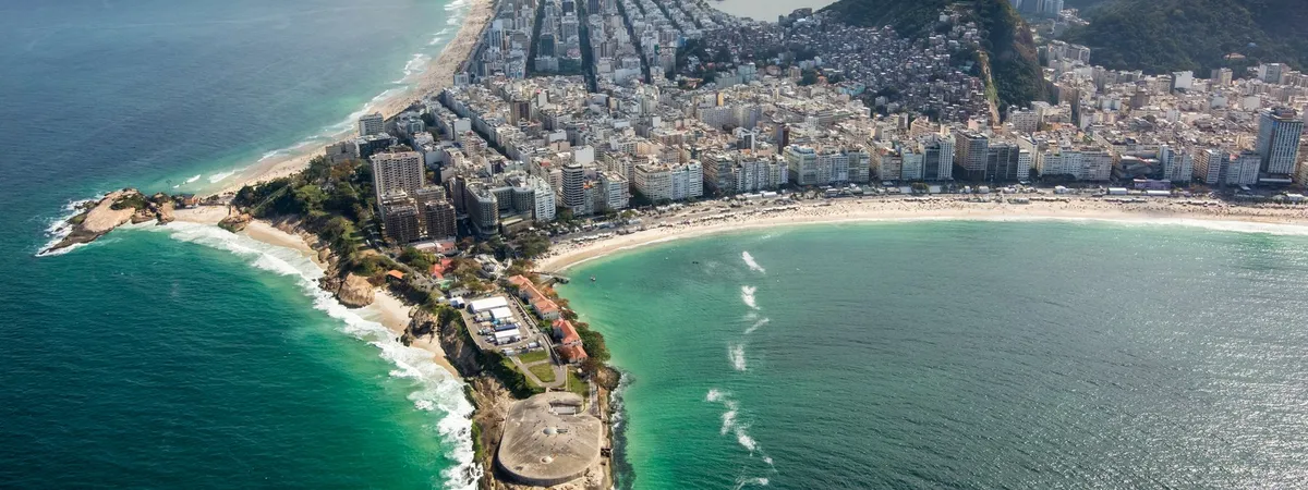 Aerial view of Copacabana Fort on its rocky headland, with the full curve of Copacabana Beach and its high-rise skyline stretching beyond