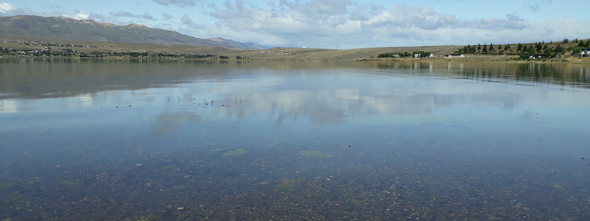 The calm waters of Bahía Redonda near El Calafate, with distant mountains and the edge of town visible along the far shore
