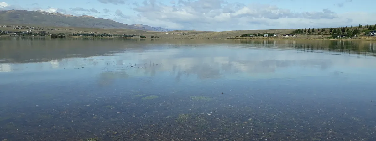 Las aguas calmas de la Bahía Redonda cerca de El Calafate, con montañas a la distancia y el borde del pueblo visible en la orilla opuesta