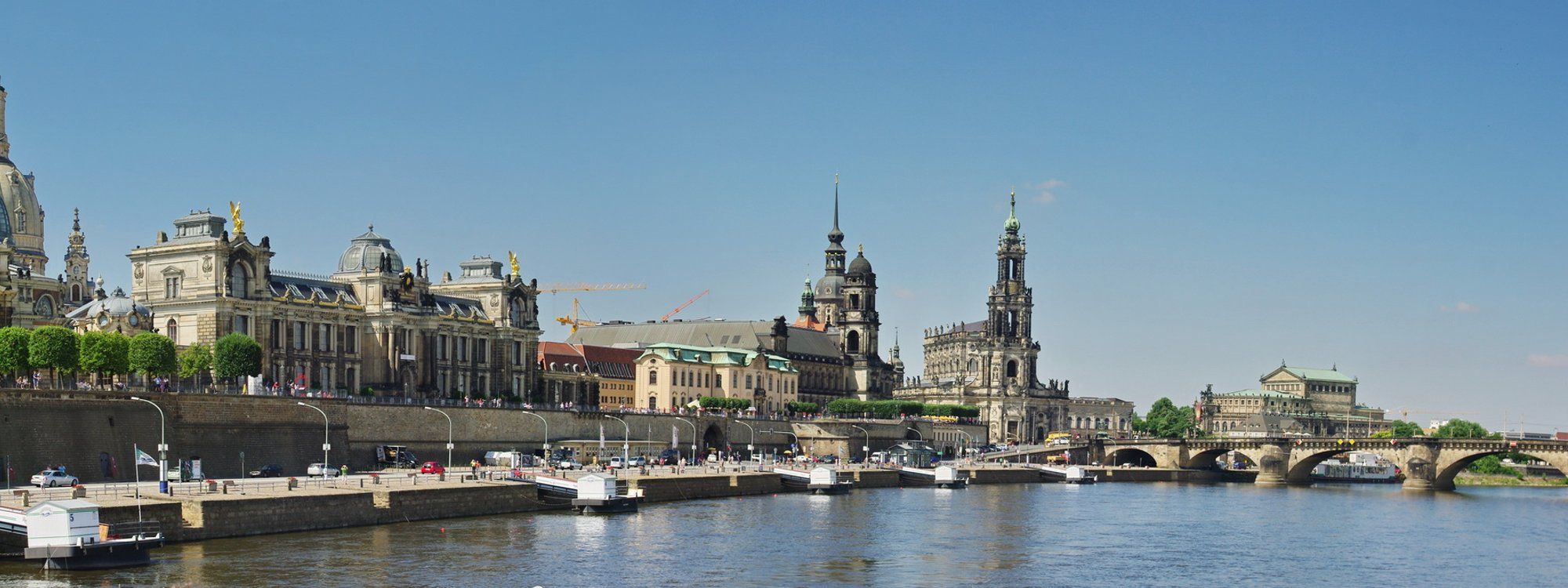 Dresden's baroque Altstadt skyline along the Elbe river, with the domes of the Zwinger, the tower of the Hofkirche, and the Semperoper visible from across the water
