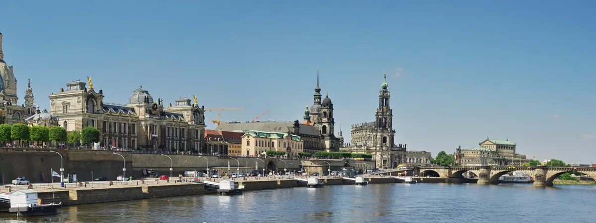 Dresden's baroque Altstadt skyline along the Elbe river, with the domes of the Zwinger, the tower of the Hofkirche, and the Semperoper visible from across the water