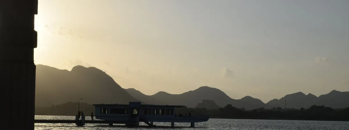 Fateh Sagar Lake at dusk, with the boat-shaped Nehru Garden food court silhouetted against the Aravalli hills