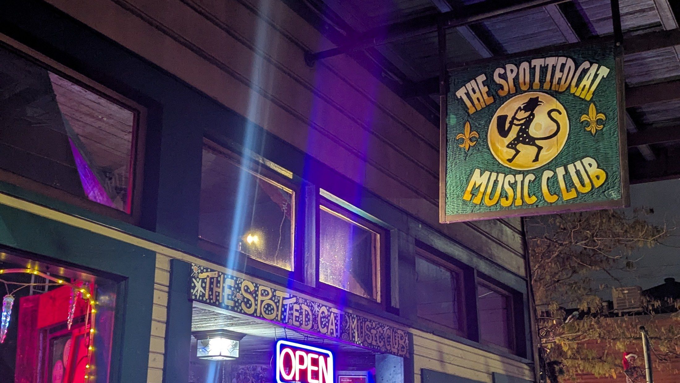 השלט הצבוע ביד של The Spotted Cat Music Club מואר בלילה ברחוב פרנצ'מן בפובור מאריני