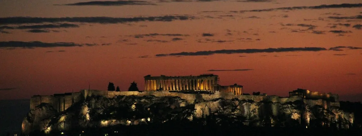 The illuminated Acropolis and Parthenon glowing above Athens at dusk