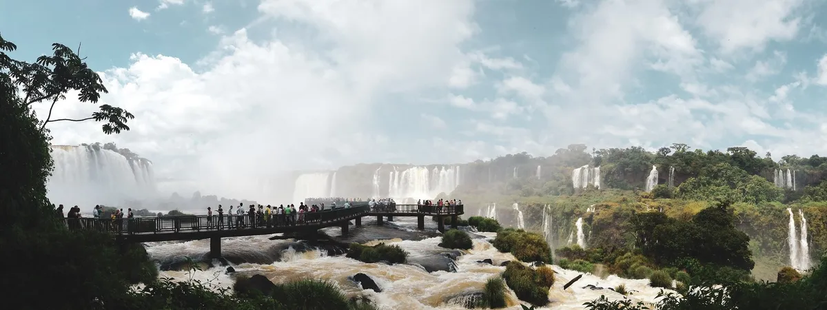 Tourists on the walkway at Iguaçu Falls' Brazilian-side viewpoints, with multiple cascades of the waterfall system framed by rainforest