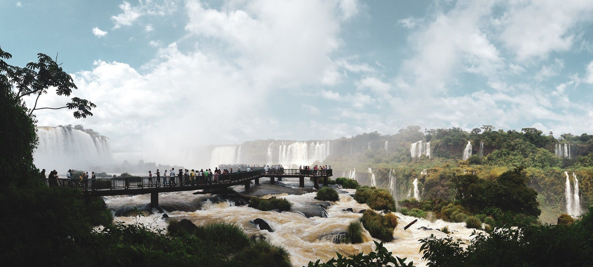 Turistas en la pasarela de los miradores del lado brasileño de las Cataratas del Iguazú, con varias caídas de agua enmarcadas por la selva