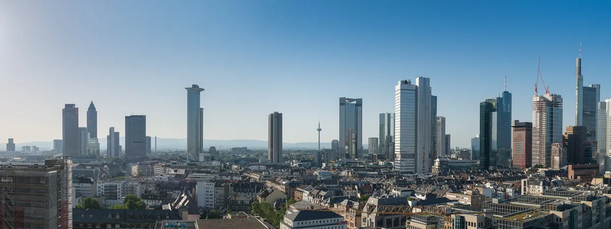 Frankfurt's skyline of glass skyscrapers seen from the south-west across the rooftops of the city, with cranes marking ongoing construction