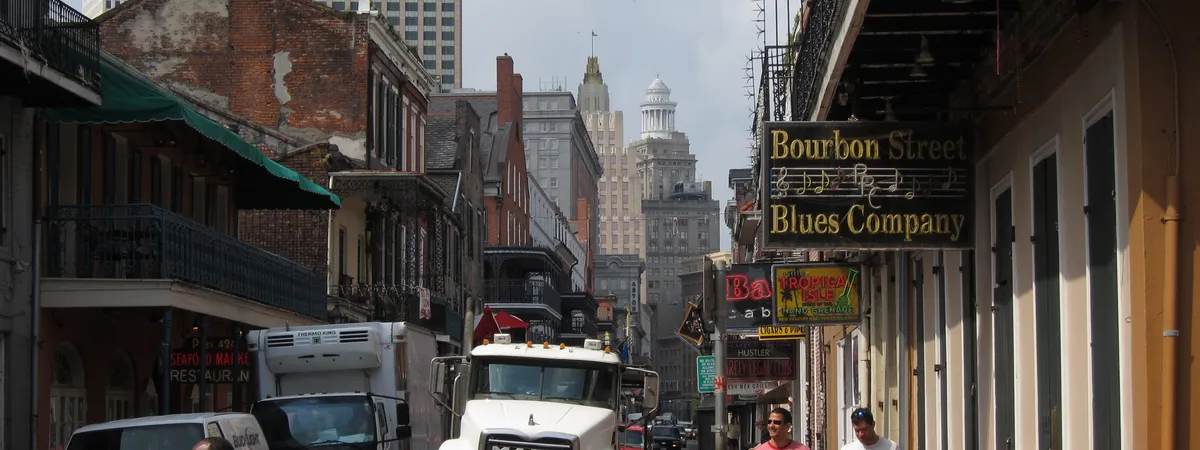 The wrought-iron balconies of Bourbon Street, with the Bourbon Street Blues Company sign hanging over the sidewalk in the French Quarter