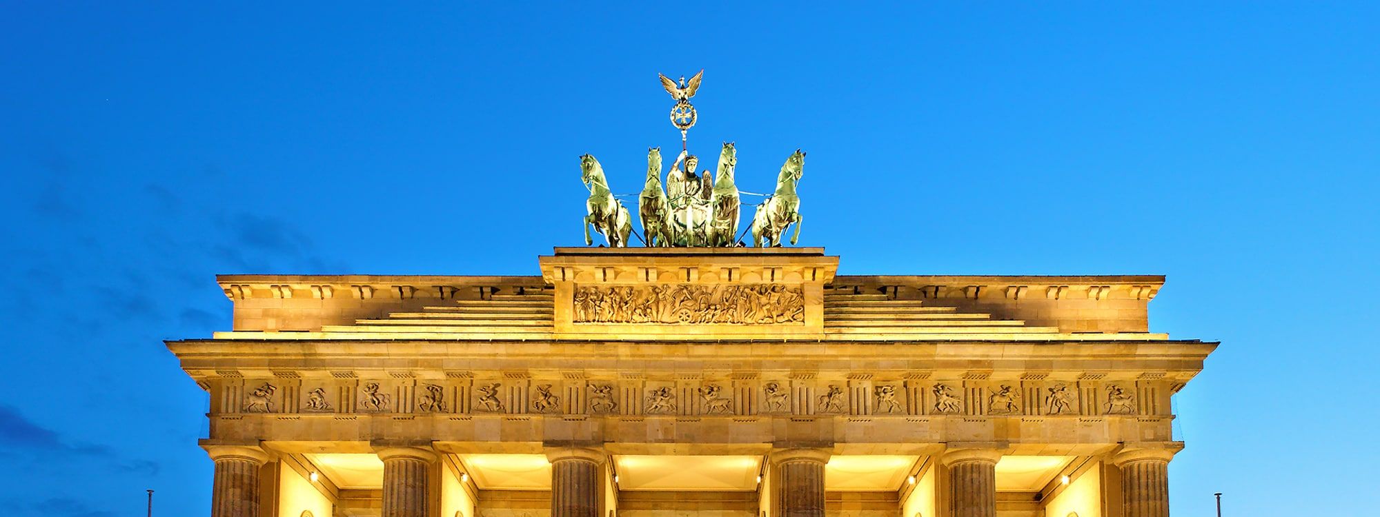 The Brandenburg Gate's Quadriga statue and pediment lit up at dusk, Berlin