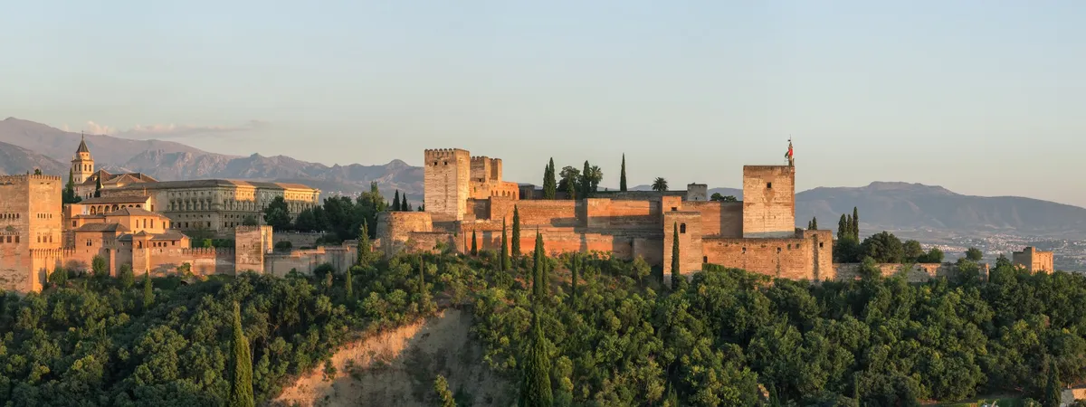 The Alhambra at sunset seen from the Mirador de San Nicolás, with the Sierra Nevada mountains behind it