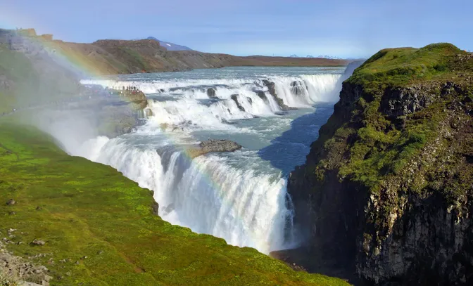 Gullfoss's two-tiered drop through its green canyon, a rainbow arcing through the spray