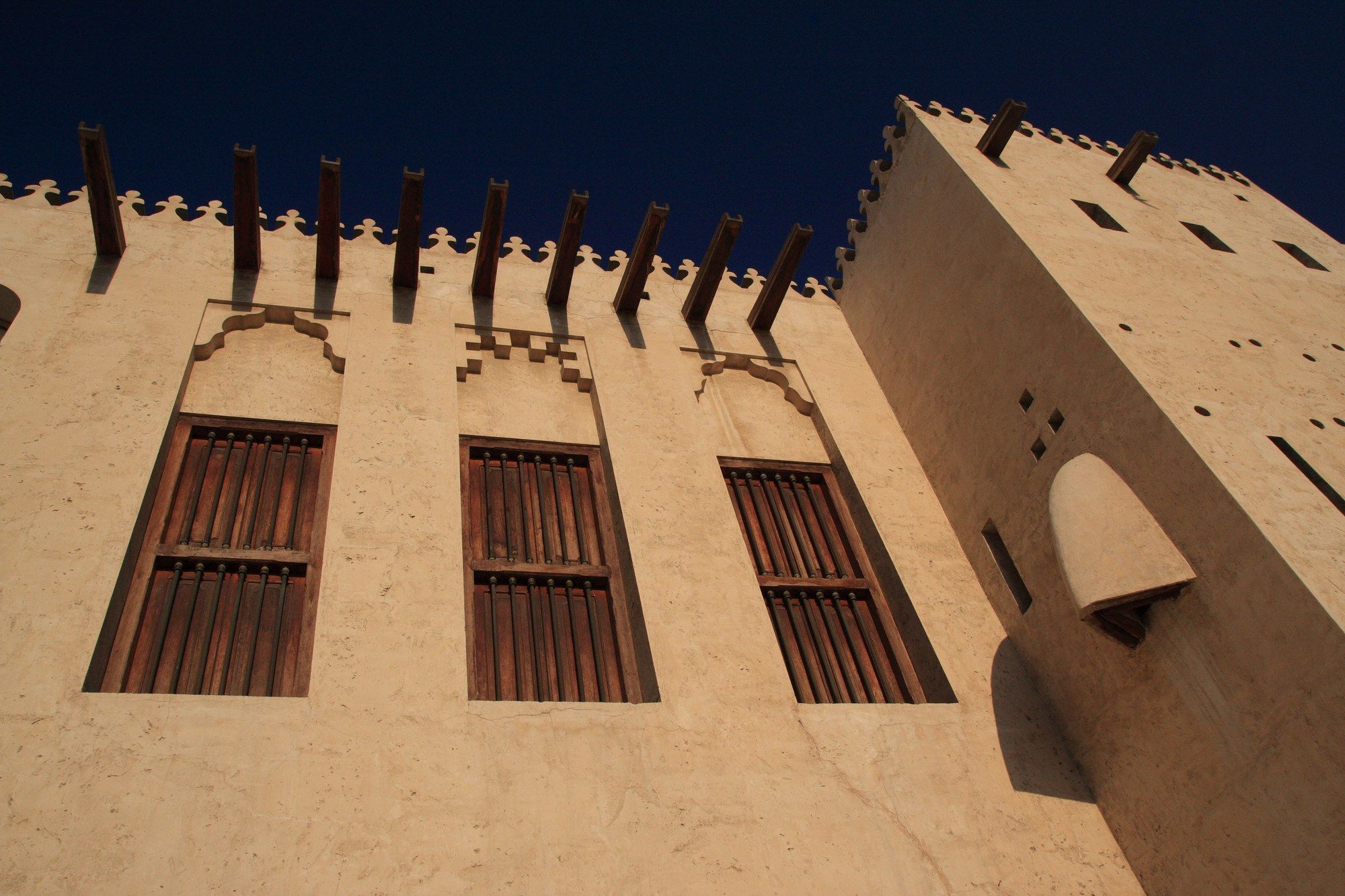 The crenellated coral-and-gypsum walls and shuttered windows of Al Hisn Fort in Sharjah's old town