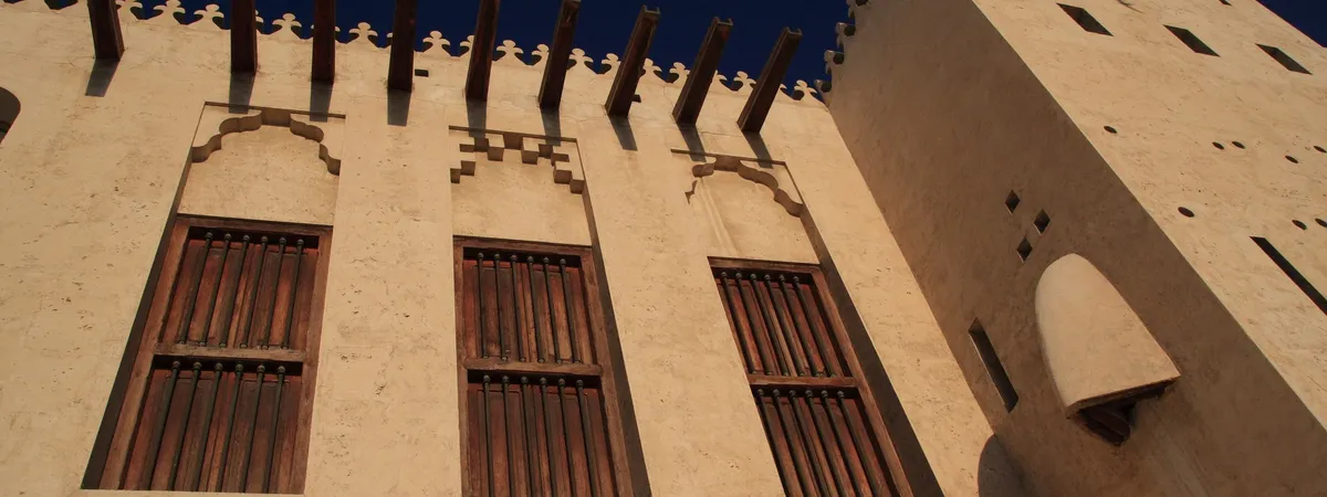 The crenellated coral-and-gypsum walls and shuttered windows of Al Hisn Fort in Sharjah's old town