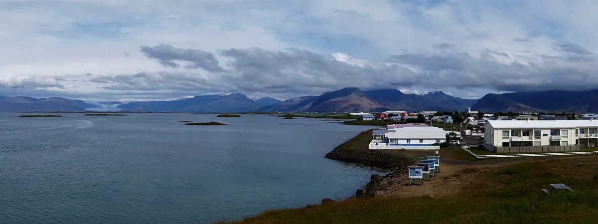 Höfn's harbor and low waterfront buildings on the Hornafjörður peninsula, with the Vatnajökull ice cap and mountains rising behind the town