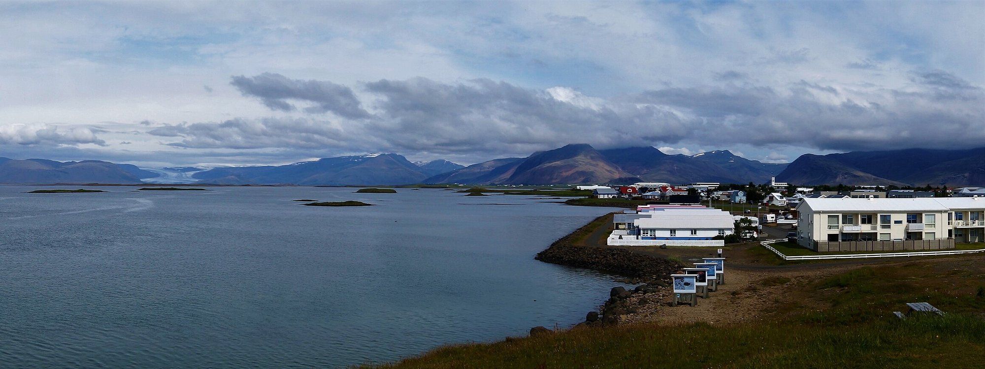 Höfn's harbor and low waterfront buildings on the Hornafjörður peninsula, with the Vatnajökull ice cap and mountains rising behind the town