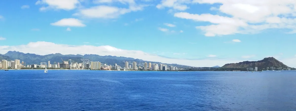 The Honolulu and Waikiki skyline along the coast, with the volcanic cone of Diamond Head rising at the far end, seen from the water