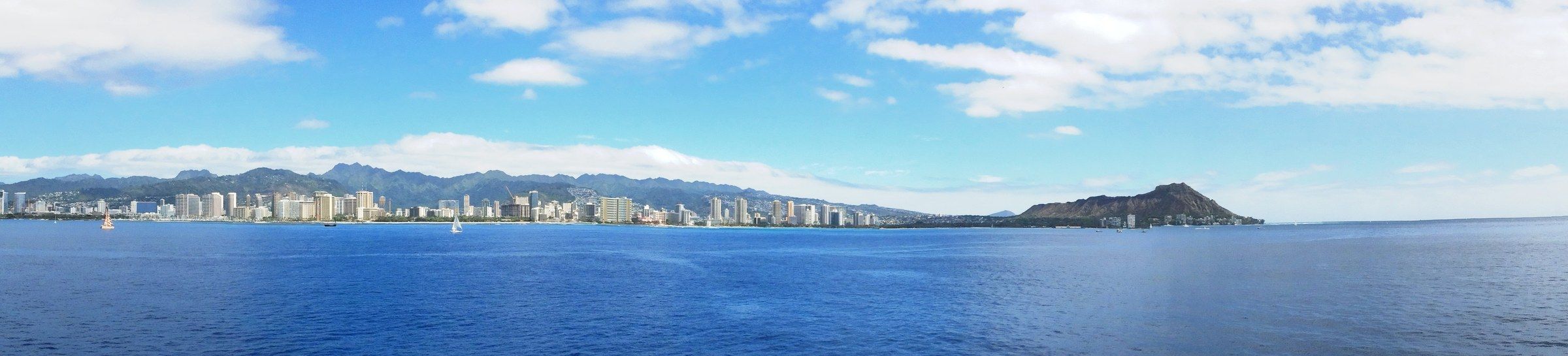 The Honolulu and Waikiki skyline along the coast, with the volcanic cone of Diamond Head rising at the far end, seen from the water