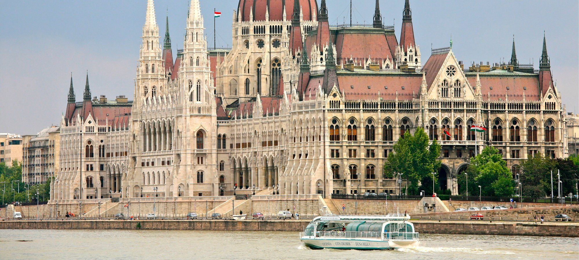 The Hungarian Parliament Building seen from across the Danube in Budapest, with a sightseeing boat passing by