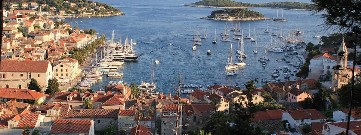 Hvar Town's harbor packed with sailboats and yachts, with the old town's red rooftops along the shore
