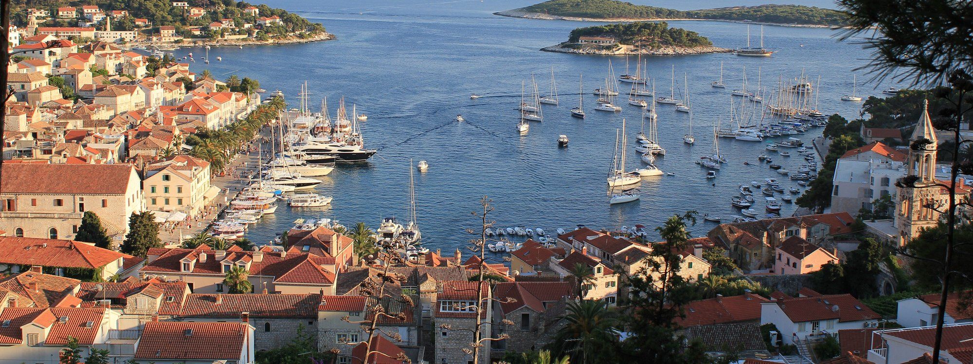 Hvar Town's harbor packed with sailboats and yachts, with the old town's red rooftops along the shore