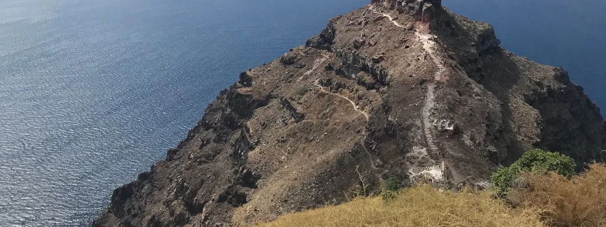 Skaros Rock, a rocky promontory jutting into the caldera below Imerovigli, with a stepped path leading to its ruined castle