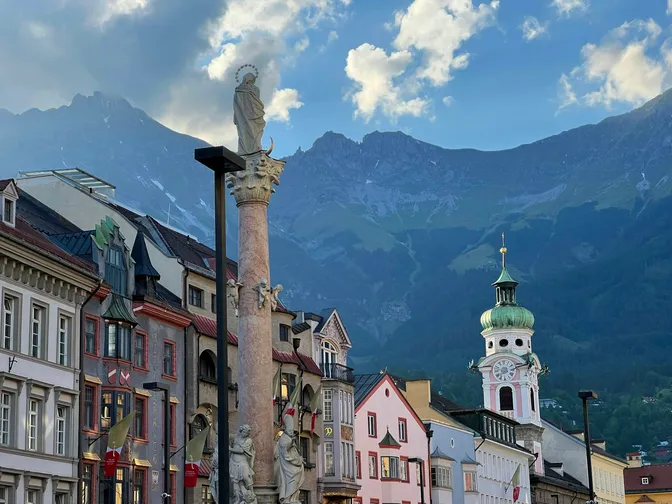 Innsbruck's old town street with the Annasäule column and painted facades, the Nordkette range rising directly behind